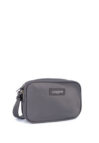 Borsa a tracolla grigia in tessuto con chiusura a zip, forma rettangolare, cinturino regolabile e una etichetta con il marchio sul davanti.