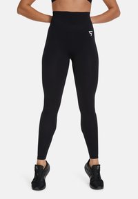 Zwarte high-waisted leggings van rekbare stof, met een logo-accent op de bovenbeen en een gladde, strakke pasvorm.