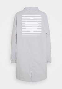 Abrigo largo gris claro con cuello, que presenta un patrón gráfico blanco de líneas horizontales y un círculo central en la parte posterior.