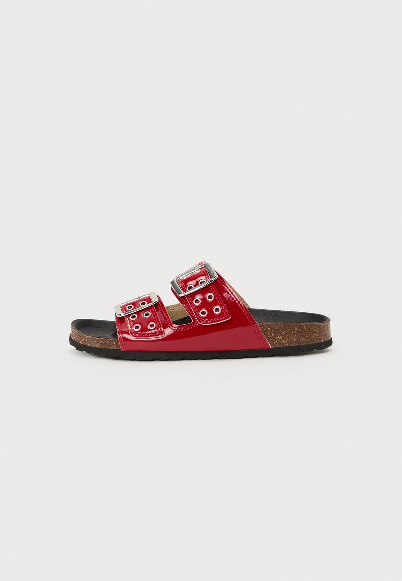 Sandales à glissière en vernis rouge avec deux boucles en métal argenté ajustables, semelle en liège et semelle extérieure en caoutchouc, avec des découpes circulaires sur les sangles.