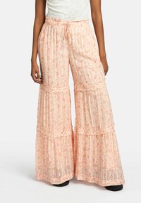 Pantalons à large jambe rose clair avec imprimé floral, accents volantés et taille élastique. Fabriqués en tissu léger et transparent.