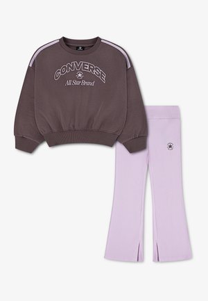 Sweat-shirt Converse marron avec logo et rayures lilas, associé à des leggings lilas avec petit logo et fentes à l'avant des jambes.