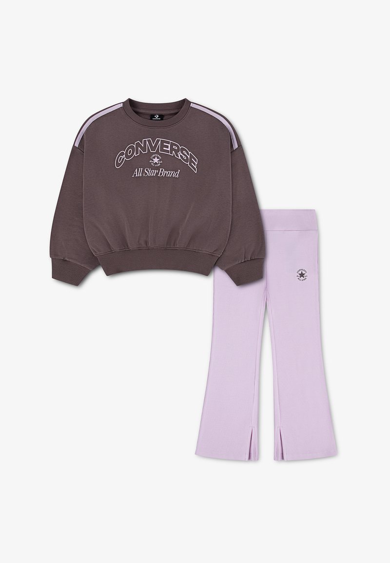 Sweat-shirt Converse marron avec logo et rayures lilas, associé à des leggings lilas avec petit logo et fentes à l'avant des jambes.