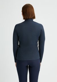 Maglietta a maniche lunghe navy con colletto alto e tessuto testurizzato, design aderente, spalle senza cuciture e cuciture minime sul retro.
