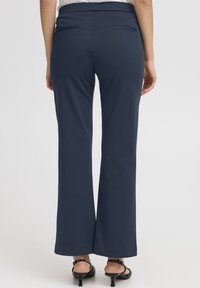 Tengerészkék, bővülő szárú nadrág puha, sima tapintású anyagból. Két hátsó zsebbel és testhezálló derékrésszel rendelkezik.