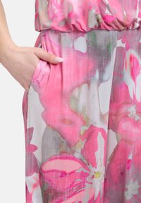 Combinaison floral avec des nuances de rose et de gris, en tissu léger, taille élastique et poche latérale. Le design présente de grands motifs de fleurs.