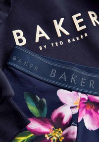 Mornarska majica s kapuco s krem vezenjem "BAKER"; tkanina s cvetnim vzorcem na robu; elastičen pas z večkratnim logotipom v modri barvi.
