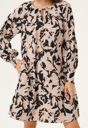 Locker sitzendes Kleid mit langen Ärmeln, schwarzem und pfirsichfarbenem abstraktem Muster, rundem Ausschnitt mit vorderem Schlüsselloch und Bindebändern sowie elastischen Bündchen.