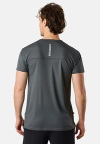 Grå atletisk t-shirt i lättvävt material. Har rund hals, korta ärmar och en vertikal etikett på baksidan.