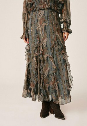 Falda maxi fluida con estampado de cachemira y capas con volantes, combinada con un top de manga larga a juego y botines oscuros de ante con tacones de madera.