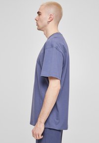 Tricou cu manșă scurtă de culoare lavandă solidă, fabricat din bumbac moale. Are o croială lejeră și gât rotund, cu detalii de cusătură minime.