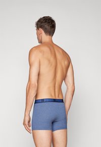 Boxeri albaștri dintr-un material moale, cu un brâu elastic bleu închis ce poartă logo-ul "PUMA". Vederea din spate evidențiază un design ajustat.