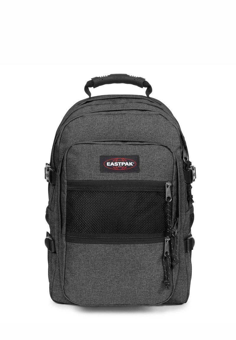 Grå tygryggsäck med ett framskjutande nätfick, dubbla dragkedjor och justerbara remmar. Eastpak-logotypen syns tydligt på framsidan.
