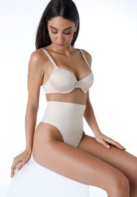 Set di reggiseno beige e slip a vita alta. Tessuto liscio ed elastico con cuciture minime. Il design presenta spalline larghe e una finitura senza cuciture.