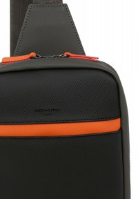 Borsa nera in tessuto con texture, dotata di una striscia arancione. Caratterizzata da una zip superiore e un logo nella parte inferiore. Cinghia regolabile per un trasporto versatile.