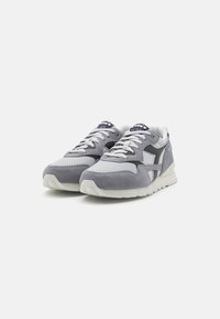 Sneaker atletiche grigie realizzate in suede e mesh, con una suola intermedia bianca, accenti scuri a contrasto e lacci con motivo.