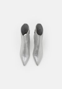 Botas de tobillo plateadas con un acabado texturizado y puntas afiladas. Cuenta con una cremallera lateral y una silueta elegante para un diseño estilizado.
