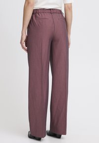 Pantaloni a gamba larga in tessuto bordeaux con finitura testurizzata. Caratterizzati da una vita elasticizzata e due tasche posteriori.
