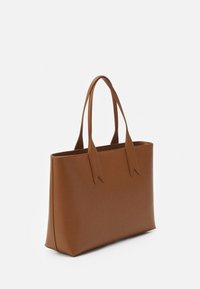 Braune Leder-Tote mit schlankem Design, verlängerten Griffen, strukturierter Form und ohne sichtbare Beschläge oder Muster. Glatte Textur.
