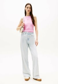 Lichtroze mouwloos topje met een vierkante uitsnede, gecombineerd met hoge taille, wijde lichtblauwe jeans en beige platform sneakers.