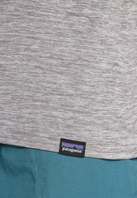 Γκρι μπλούζα φανέλα από μαλακό, υφασμένο ύφασμα. Διαθέτει ένα μαύρο λογότυπο Patagonia στο κάτω μέρος. Προσφέρει άνετη, χαλαρή εφαρμογή.