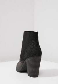 Stivaletto nero alla caviglia con retro a motivo rettile testurizzato, parte anteriore liscia, pannelli laterali elastici e suola con tacco spesso.