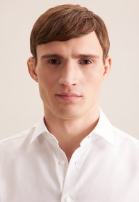 Camicia bianca con bottoni realizzata in tessuto leggero; presenta un colletto classico, una texture liscia e nessun motivo o dettaglio visibile.