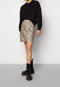 Black sweater, leopard-print satin skirt in beige and black, and black lace-up boots with textured soles. Skirt has a fitted silhouette.