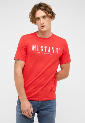 Red short-sleeve t-shirt with crew neckline, featuring white printed text "MUSTANG JEANS COMPANY SINCE 1932" on the front.