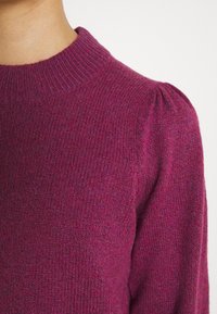 Różowy sweter dzianinowy z prążkowanym okrągłym dekoltem i bufkami, wykonany z teksturowanej tkaniny, dopasowany.