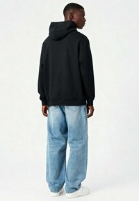 Mustmustar, millel on suur kapuuts, lõbus lõige, soonikkoes mansetid, kombineeritud helesiniste laiate pükste ja valgete tennistega. Sile puuvillane tekstuur.