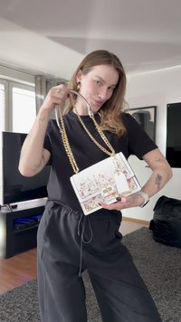 Witte handtas met bloemenpatroon, gouden kettingbandje en een sluiting met gesp. Glad materiaal, rechthoekige vorm, met een afneembare label.