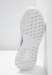 White athletic shoe sole with grid pattern and textured sections. Features subtle purple accents and embossed logo detailing.