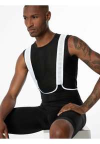 Schwarzes Sporttanktop mit weißen Mesh-Trägern und eng anliegenden schwarzen Shorts. Das Design betont Atmungsaktivität, mit strukturiertem Stoff und sichtbaren Nähten.