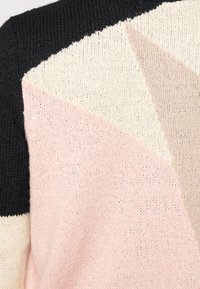 Strickpullover mit geometrischem Design in Schwarz, Pink, Cremé und Beige, der eine weiche Textur und auffällige Farbkombinationen präsentiert.