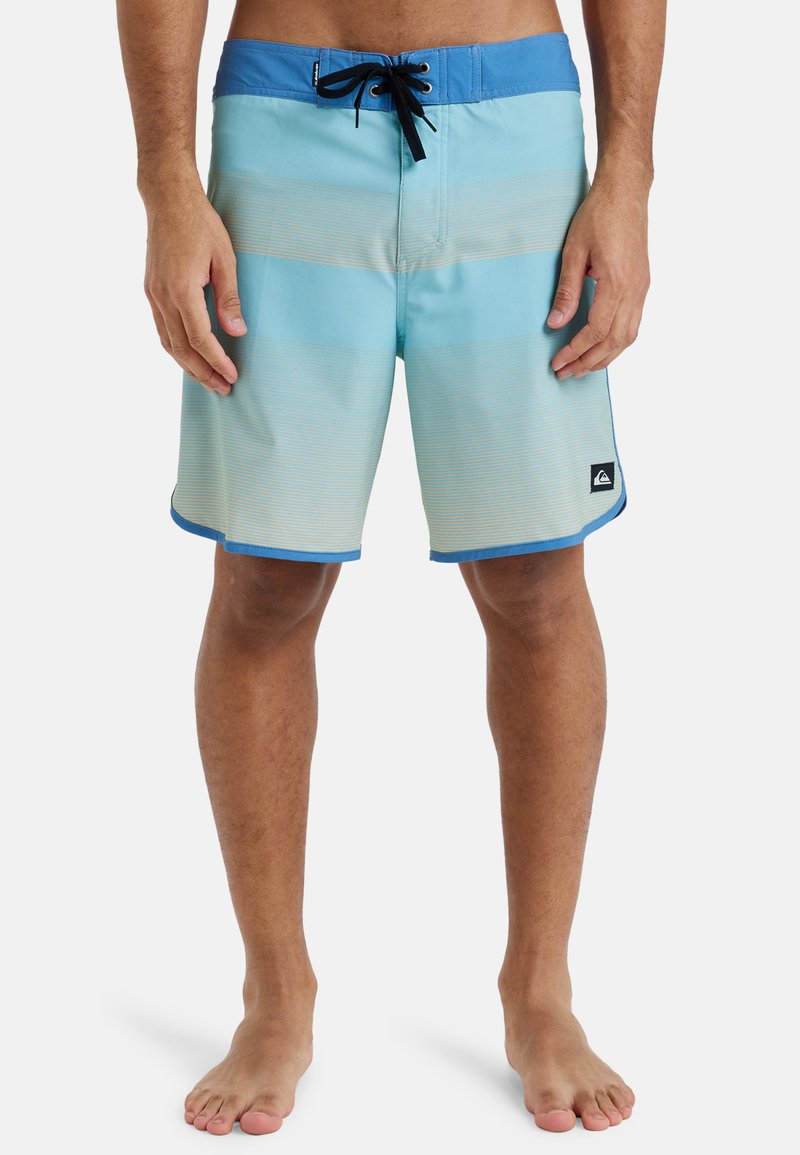 Blau- und hellblaue gestreifte Boardshorts aus leichtem Material, mit schwarzem Kordelzug und seitlichem Logopatch. Mittlere Oberschenkellänge mit glatter Textur.