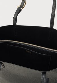 Melnas ādas pleca soma ar fakturētu virsmu, zelta rāvējslēdzēju un iekšējo kabatu. Aprīkota ar divām siksnām un uzņēmuma nosaukumu iemarinēts iekšpusē.