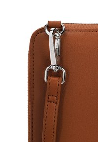 Brown leather bag corner featuring a silver zipper pull and a looped strap attachment with a smooth texture, contrasted by stitched edging.
