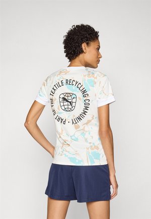Witte t-shirt met een aquamarijn en beige gemarmerd patroon, met een cirkelvormige grafiek en tekst over textielrecycling op de achterkant. Gecombineerd met marineblauwe shorts.