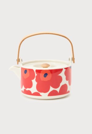 Théière en céramique blanche avec de grands motifs de fleurs de coquelicot rouges, couvercle avec bouton en bois et poignée en bois courbée sur fond clair.