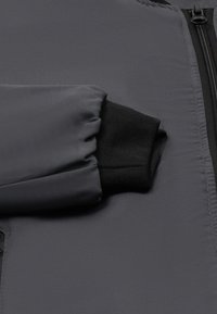 Dunkelgraue Daunenjacke mit geripptem schwarzen Bündchen, glatter Textur und Reißverschluss vorne, entworfen für Wärme und Komfort.