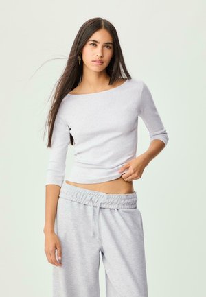 Light gray, fitted long-sleeve top with a wide neckline, paired with matching gray, elastic-waste joggers in a soft, textured material.
