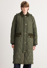Groene gewatteerde parka met een kraag en twee opgestikte zakken, voorzien van gouden drukknoopknopen en een rits aan de voorkant, gemaakt van een stof met textuur.