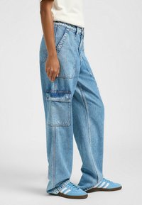 Pantaloni cargo in denim azzurro chiaro con una vestibilità comoda, caratterizzati da grandi tasche laterali, cuciture a vista e un design a vita alta.