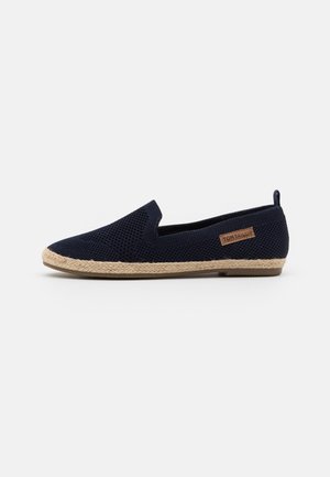 Chaussure tissée bleu marine à enfiler avec semelle tressée beige et languette au talon, avec une petite étiquette de marque Tom Tailor marron sur le côté.