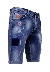 Denim shorts in donkerblauw met verwerkte details. Voorzien van patches, rafelige randen en een schedel-embleem op de voorzak. Knopenluiting.