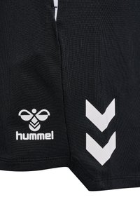 Bermudas deportivas negras hechas de un tejido texturizado, con un logotipo blanco y dos patrones de chevrón blancos a los lados.