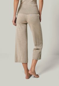 Beige, weit geschnittene, verkürzte Hose aus strukturiertem Stoff mit einem leichten Glanz und einem Bund mit einem Logodetail auf der Rückseite.