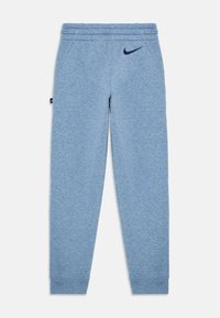 Modre Nike trenirke z elastičnim pasom, stranskimi žepi, zaprtimi gležnji in črnim Nike logotipom na zgornjem levem stegnu ter stransko oznako.