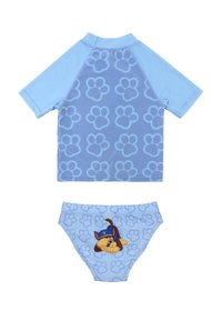 Conjunto de baño de dos piezas azul que incluye una parte superior de manga corta con huellas de patas azules y unas braguitas a juego con un diseño de perro de dibujos animados.